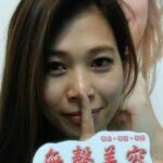 顧客女性,手指比出「噓」的手勢並拿著「無聲美容」標語牌,象徵品牌理念中的「不推銷、不誇張、不話術」
